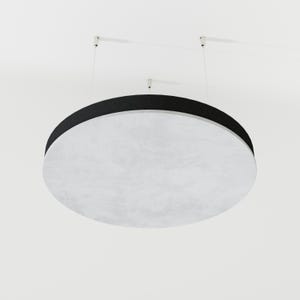 May include: A large, circular acoustic panel suspended from the ceiling. The panel has a white, textured surface with a thick black border. It is attached to the ceiling by thin, white cables.