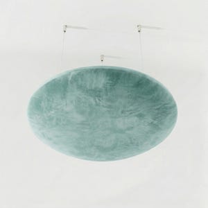 May include: A large, oval-shaped, light teal-colored ceiling light fixture. The fixture is suspended from the ceiling by thin white cords. The surface of the light has a textured, marbled appearance.