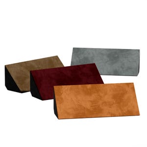 Puede incluir: Cuatro almohadas rectangulares en tonos marrón, burdeos, naranja y gris. Cada almohada tiene una superficie texturizada y una base triangular negra. Las almohadas están dispuestas en diferentes ángulos, mostrando sus variados colores y texturas.