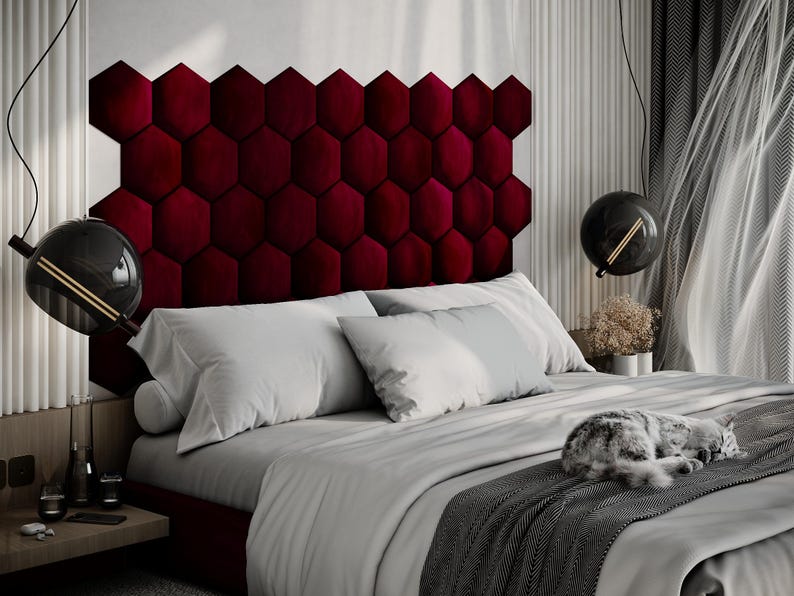 Puede incluir: Un dormitorio moderno con una cama con un cabecero burdeos en forma de hex&aacute;gono. La cama est&aacute; cubierta con ropa de cama blanca y una manta gris. Un gato est&aacute; durmiendo en la cama. L&aacute;mparas negras en forma de globo cuelgan del techo.