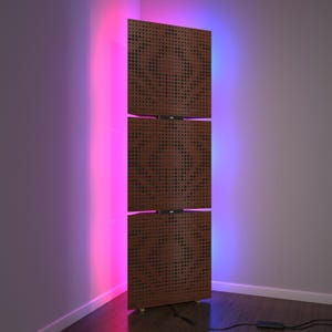Könnte beinhalten: Ein moderner Raumteiler mit drei Paneelen und einem braunen, gepunkteten Muster. Die Paneele werden von rosa und blauen LED-Leuchten beleuchtet. Der Raumteiler steht auf einem Holzboden.