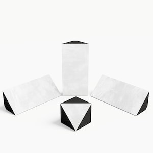 Könnte beinhalten: Geometrische Formen in Schwarz und Weiß. Das Bild zeigt ein hohes rechteckiges Prisma, einen Würfel und zwei dreieckige Prismen. Die Formen haben eine weiße Oberfläche mit einer schwarzen Basis oder Oberseite. Der Würfel hat ein weißes Dreieck auf jeder Seite.