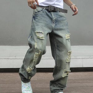 Men's Ripped Denim Jeans | High Waisted Distressed Pants | Streetwear Y2k Vintage Fashion
.
A pair of men's ripped denim jeans with a relaxed, distressed design and streetwear-inspired silhouette. The jeans feature a loose fit, visible rips, and casual styling ideal for Y2K, grunge, or vintage outfits.