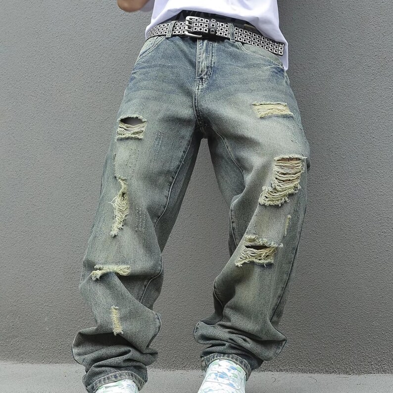 Men's Ripped Denim Jeans | High Waisted Distressed Pants | Streetwear Y2k Vintage Fashion
.
A pair of men's ripped denim jeans with a relaxed, distressed design and streetwear-inspired silhouette. The jeans feature a loose fit, visible rips, and casual styling ideal for Y2K, grunge, or vintage outfits.