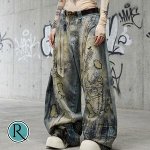 May include: Light blue distressed denim jeans with multiple zippers and detailed stitching. The wide-leg jeans have a faded, worn look, showcasing a unique artistic design. The jeans have a relaxed fit and a vintage aesthetic.
