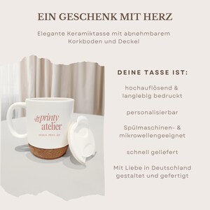 May include: White ceramic mug with a cork base and a white lid. The mug has the text "printy atelier" in pink. The image also includes text in German: "EIN GESCHENK MIT HERZ" and "DEINE TASSE IST:"