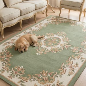 Può includere: Un tappeto rettangolare verde con un bordo floreale e un design centrale. Il tappeto presenta un bordo color crema con motivi floreali nei toni del rosa, marrone e verde. Un cucciolo di golden retriever è sdraiato sul tappeto.