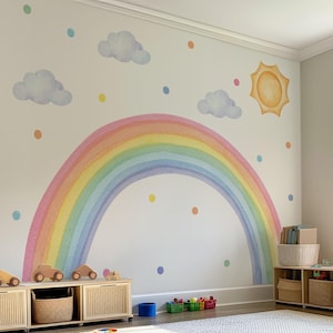 May include: A whimsical nursery wall mural featuring a large watercolor rainbow, sun, clouds, and polka dots. The room includes wooden toy cars, storage baskets, and a white rug. The text at the bottom reads: "If you want it to be like this picture, you need to buy Large Sun / XXLarge Rainbow / XLarge Cloud / Polka Dots."