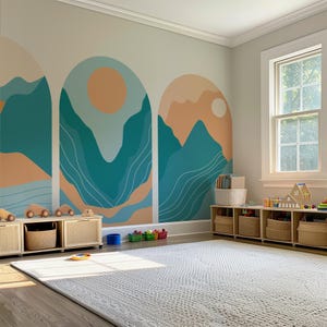 May include: A playroom with a large, light-coloured rug and a wall mural featuring teal and peach mountain and sun designs. Wooden toy cars sit atop a low cabinet with woven baskets. A window lets in natural light.
