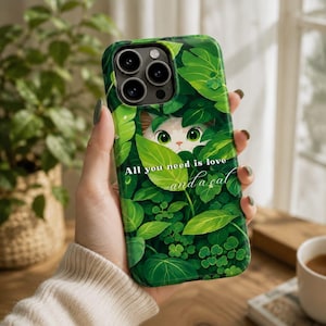 May include: Green phone case featuring a cat peeking through leaves. The case has a vibrant green leaf design with the text "All you need is love and a cat" in white script. The phone case is designed to fit a smartphone.