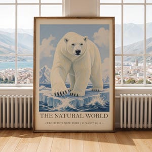 May include: A framed poster depicting a polar bear on an iceberg, set against a light blue sky with clouds. The poster includes the text "THE NATURAL WORLD - EXHIBITION NEW YORK | JUN-OCT 2011 -" at the bottom.