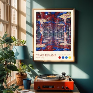 Könnte beinhalten: Gerahmter Kunstdruck einer Yayoi Kusama-Ausstellung in Chicago. Das Kunstwerk zeigt einen verspiegelten Raum mit roten, blauen und gelben kreisförmigen Mustern. Ein Vintage-Plattenspieler in Orange befindet sich darunter.