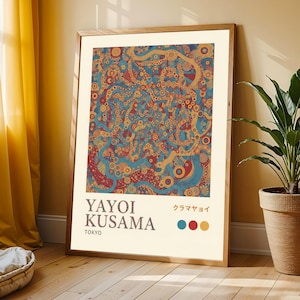 May include: A framed art print with an abstract design in blue, red, and yellow. The print features the text "YAYOI KUSAMA TOKYO" and Japanese characters. The artwork is presented in a wooden frame, suitable for wall display.