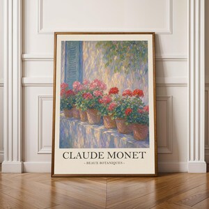 May include: A framed art print featuring a Claude Monet painting titled Beaux Botaniques. The artwork depicts a row of potted red geraniums on a ledge against a textured wall with blue shutters, rendered in an impressionist style with visible brushstrokes.