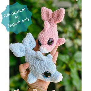 May include: Two handmade crochet dolphins, one light blue and one pink, with large, expressive eyes. The dolphins are labeled "Neera: the Indian River Dolphin" and the image includes the text "PDF pattern in English only" and the seller's Instagram handle.