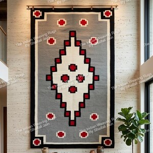 Pode incluir: Tapete cinza retangular grande com um design geométrico em vermelho, preto e branco. O tapete está pendurado em uma parede clara. O texto "The Indian Weaving Rugs By Shaifali Jain" é repetido na parede.