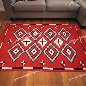 Può includere: Un tappeto rettangolare rosso con un motivo geometrico. Il design presenta forme a diamante in bianco, grigio e nero, con croci bianche al centro. Il tappeto ha un bordo bianco e nero ed è posto su un pavimento in legno.