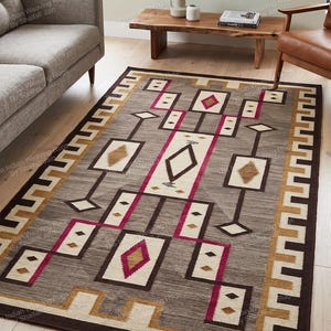 Peut inclure: Un tapis rectangulaire présentant un fond gris avec un motif géométrique dans des tons de brun foncé, crème, beige et magenta. Le design comprend des formes de losanges interconnectées, des bordures rectangulaires et un motif en escalier.