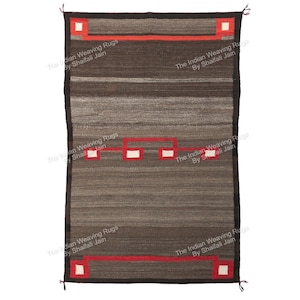 May include: A rectangular, handwoven rug with a brown and grey striped pattern. The rug features red and white geometric designs along the edges and in the centre. The border is dark brown. The Indian Weaving Rugs by Shaifali Jain.