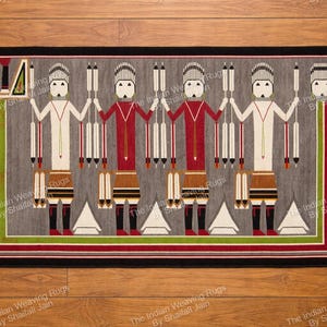 Puede incluir: Alfombra rectangular gris con borde negro y borlas. La alfombra presenta un patrón repetido de figuras estilizadas en rojo, blanco y marrón, sosteniendo elementos verticales. El diseño está enmarcado por rayas verdes y rojas.