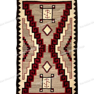 May include: Rectangular woven rug with a geometric pattern. The rug features a central gray field with red, black, and white geometric designs. The border is black with a zigzag pattern. The rug is likely made of wool or a similar material.