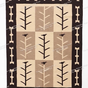 Può includere: Un tappeto rettangolare tessuto con un design geometrico. Il tappeto presenta un bordo marrone scuro con forme ripetute di frecce e diamanti. Il campo centrale ha un motivo a griglia con alberi e uccelli.