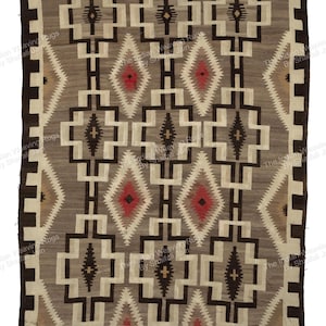 Può includere: Un tappeto rettangolare tessuto con un motivo geometrico. Il tappeto presenta un campo centrale grigio con forme ripetute di diamanti e quadrati in nero, bianco e rosso. Il bordo è marrone scuro.