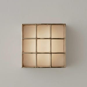 Könnte beinhalten: Ein quadratisches Wandregal mit neun Fächern und metallischem Finish. Jedes Fach hat eine quadratische Form mit einer warmen, neutralen Farbe. Das Regal ist an einer hellgrauen Wand befestigt und schafft eine minimalistische Ästhetik.