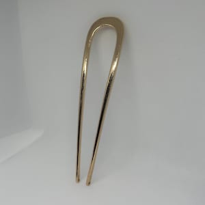 Peut inclure: Une &eacute;pingle &agrave; cheveux dor&eacute;e avec un dessus en forme de U et deux longues broches droites. L'accessoire pour cheveux est en m&eacute;tal et a une finition brillante. L'&eacute;pingle est con&ccedil;ue pour maintenir les cheveux en place.