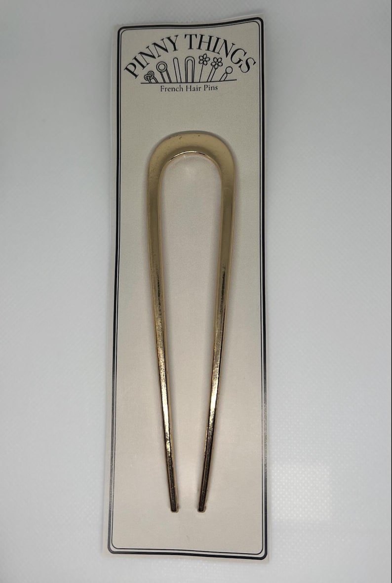 Peut inclure: &Eacute;pingle &agrave; cheveux fran&ccedil;aise dor&eacute;e, en forme de U. L'&eacute;pingle est pr&eacute;sent&eacute;e sur une carte cr&egrave;me avec le texte "PINNY THINGS" et "French Hair Pins" en noir. L'&eacute;pingle mesure environ 15 cm de long.