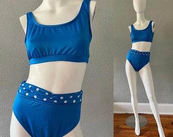 Puede incluir: Un traje de baño de dos piezas en azul vibrante. La parte superior es de estilo cuello redondo, y la parte inferior de cintura alta presenta una cintura de lunares blancos. El traje de baño se exhibe en un maniquí.