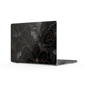 May include: A laptop computer featuring a protective hard shell case with a dark black floral pattern. The design displays large, layered black flowers with thin, metallic gold outlines and textured petals, covering the entire outer lid surface.