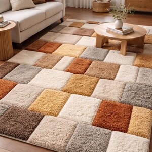 Puede incluir: Una alfombra de área con diseño de cuadrados en un salón. La alfombra presenta un diseño de patchwork con cuadrados beige, marrón y naranja. Está colocada sobre un suelo de madera, complementando la cálida paleta de colores de la habitación. Medidas: 200 cm x 300 cm.