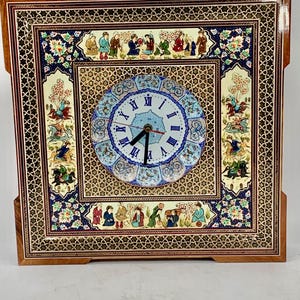 Könnte beinhalten: Quadratische Holzuhr mit aufwendigen Mosaik- und Maldetails. Das Zifferblatt ist von einem floralen Design umgeben und zeigt römische Ziffern. Der Rand der Uhr hat ein detailliertes geometrisches Muster und ist mit hellem Braunholz akzentuiert.
