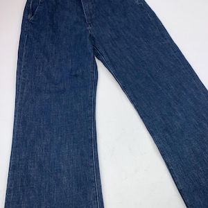 May include: Dark blue denim pants with a classic five-pocket design. The pants have a straight leg and a button and zipper closure. The waistline features belt loops. The pants are made of a sturdy denim material.