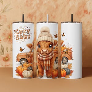 Puede incluir: Vaso blanco con un diseño de temática otoñal. El diseño presenta una vaca de las Tierras Altas marrón con sombrero y bufanda, calabazas, mariposas y una camioneta vintage. También se incluye el texto "Cozy Baby".