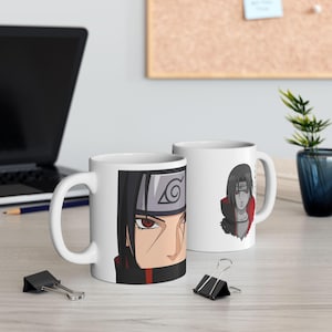 May include: Two white ceramic mugs with black handles. One mug features a close-up of a character's face with red eyes and a grey headband. The other mug displays a full-body illustration of the same character in a red and black outfit.