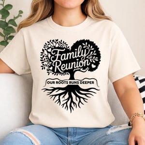 Könnte beinhalten: Cremefarbenes T-Shirt mit einem schwarzen Baum-Grafikdesign. Der Baum hat eine herzförmige Krone mit dem Text "Family Reunion" und "OUR ROOTS RUNS DEEPER". Ein lässiges Kleidungsstück, ideal für Familientreffen.