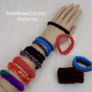May include: A collection of crocheted bracelets in various colors, including red, orange, yellow, purple, blue, black, and brown. The bracelets are stacked on a mannequin's arm, with some additional bracelets lying on a white surface. The text "JadeRoseCrochet Patterns" is visible at the top of the image.