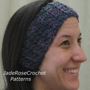 Puede incluir: Una diadema de crochet morada y gris que lleva una persona con el pelo largo y oscuro. La diadema es gruesa y cubre las orejas. La persona sonríe y mira hacia la derecha.