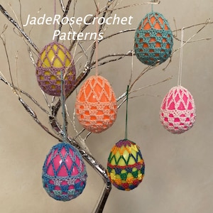 May include: Six crocheted Easter egg covers in various colours, including pink, yellow, orange, blue, and green, hanging from a branch. The eggs are decorated with different crochet patterns.
