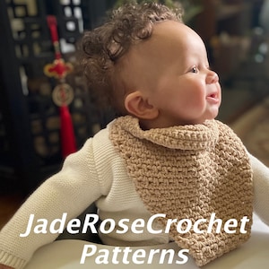 Puede incluir: Primer plano de un bebé con una bufanda de ganchillo beige. El bebé tiene el pelo castaño rizado y mira hacia la derecha. El texto "JadeRoseCrochet Patterns" es visible en la parte inferior de la imagen.