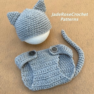 May include: Gray crocheted cat hat and diaper set with buttons.  The hat has cat ears and the diaper has a tail.  JadeRoseCrochet Patterns.
