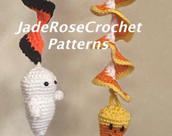 May include: Crocheted Halloween decorations featuring a white ghost and a candy corn design. The decorations are attached to orange and black, and orange, yellow, and white spiral streamers. The text "JadeRoseCrochet Patterns" is visible.