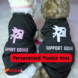 Op de afbeelding: Twee knuffels dragen zwarte vesten met de tekst "SUPPORT SQUAD" en een afbeelding. De vesten hebben ook de tekst "Personalised Plushie Vest". Eén vest heeft roze afbeeldingen, de andere witte. Het Plushie-logo staat onderaan.
