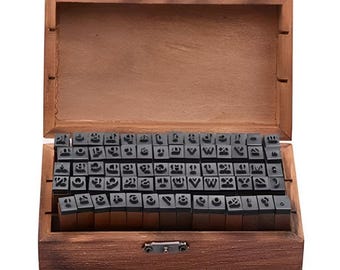 May include: A wooden box with a hinged lid, filled with individual letter stamps. The stamps are black and arranged neatly inside the box. The box is made of a dark brown wood.