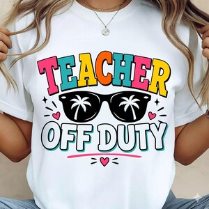 May include: White t-shirt with the words "TEACHER OFF DUTY" in colorful block letters and a pair of sunglasses with palm tree designs. The design includes hearts and starbursts.