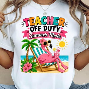 May include: White t-shirt with a colorful graphic featuring a pink flamingo in sunglasses relaxing on a beach chair. The text reads "TEACHER OFF DUTY Summer Mode" in bright colors, with a palm tree and hibiscus flowers.