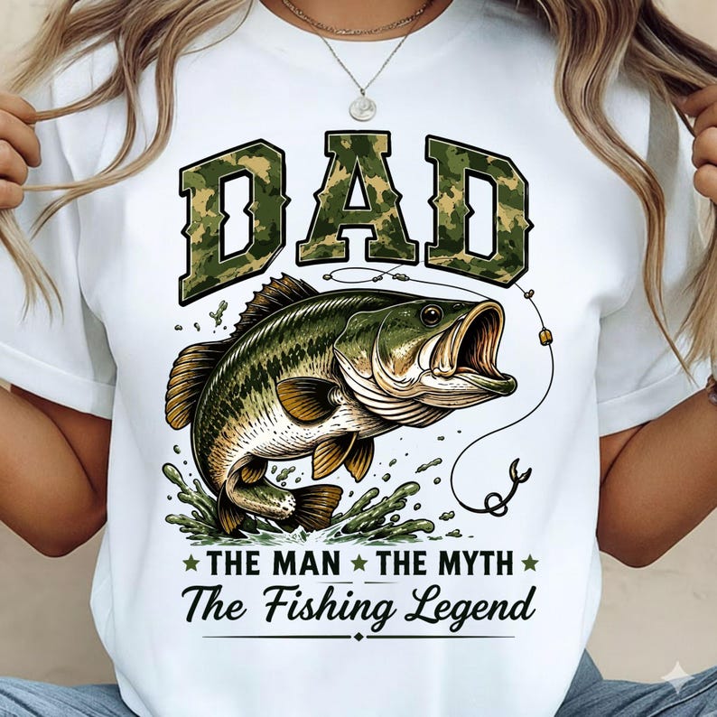 May include: White t-shirt with a graphic of a largemouth bass jumping out of water. The word "DAD" is in camouflage lettering above the fish, with the text "THE MAN THE MYTH The Fishing Legend" below.