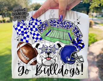 May include: White t-shirt with a football theme. The design includes a brown football, a bulldog wearing star-shaped glasses, a blue football helmet, and a stadium graphic. The text "Go Bulldogs!" is also featured.